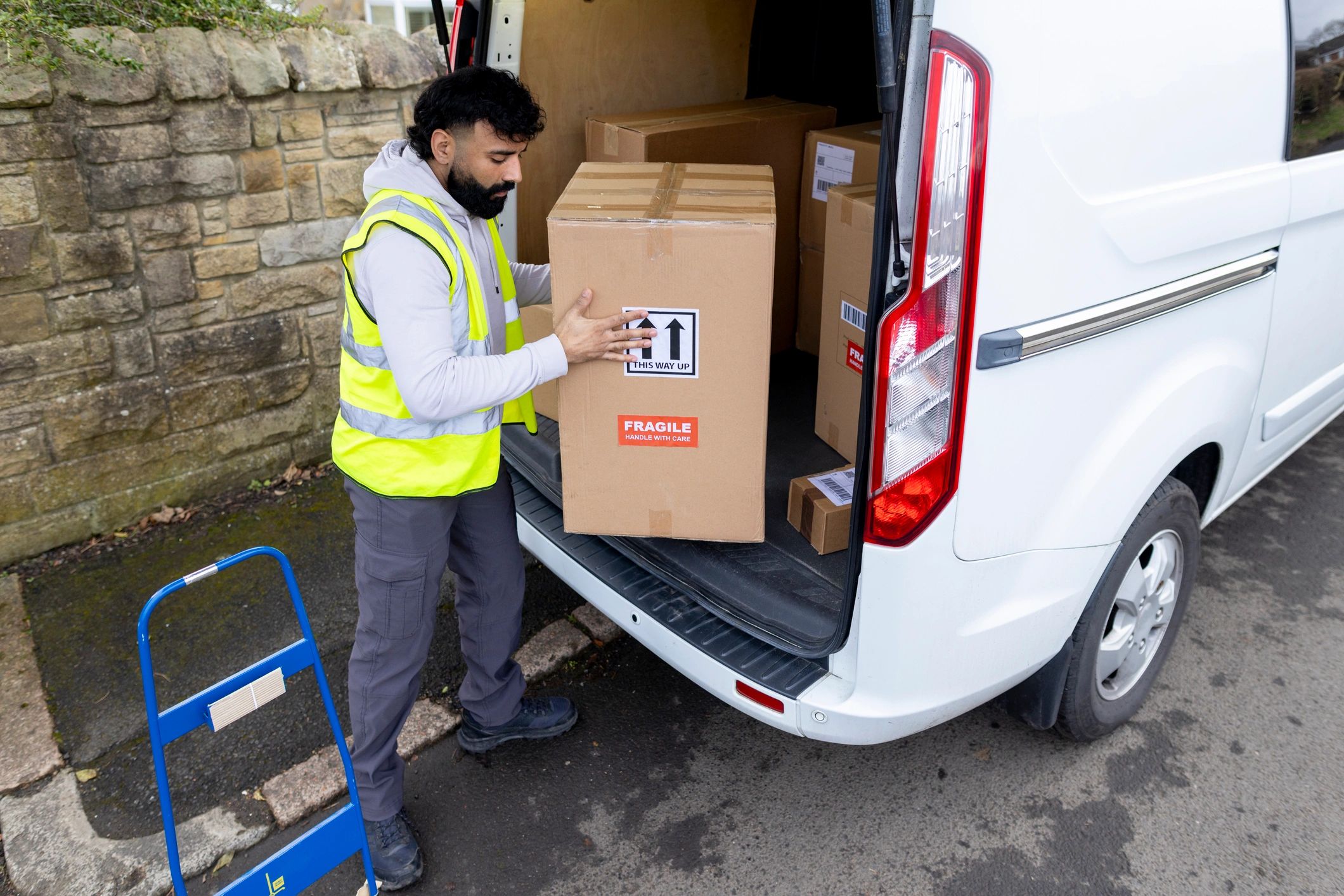 Delivery driver unloading packages from a van
